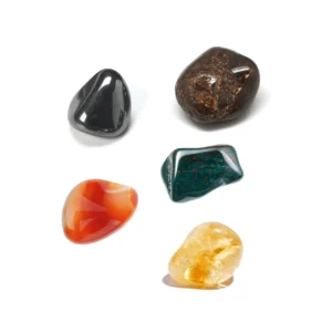 Top-down studio view of five polished natural tumbled crystals for the Aries zodiac sign arranged cleanly on a solid white background.