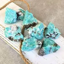 A neat pile of rough Amazonite crystals exhibiting bright, highly saturated turquoise-blue colors and rough, unpolished edges against a seamless white background.