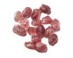 A scattered cluster of small, semi-translucent strawberry quartz stones isolated on a pure white background, displaying glossy red-pink surfaces and natural internal mineral flecks.