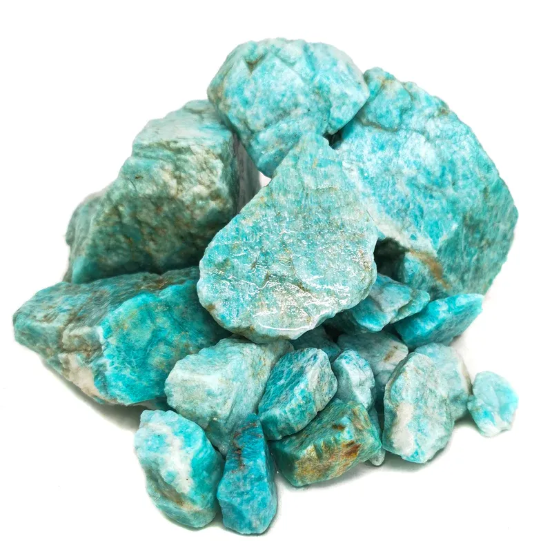 Amazonite crystal chunks displayed on a rustic, white-painted wooden board with a rope handle, showcasing their natural turquoise color and dark smoky inclusions.