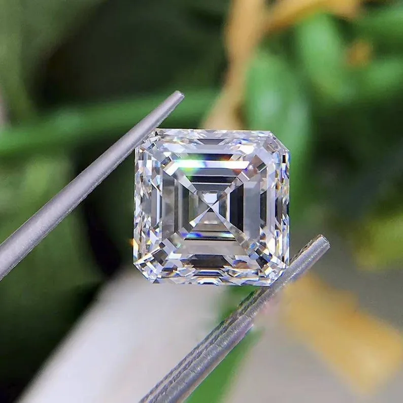 A close-up of a loose, Asscher cut D-color moissanite stone held in jeweler's tweezers, showcasing its deep step-cut facets and brilliant rainbow fire.