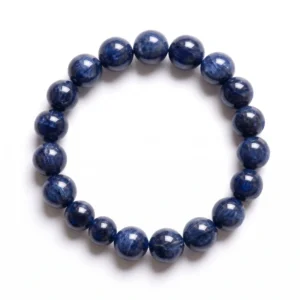 Top-down commercial product photograph of a natural, premium gem-grade non-heated and non-treated Blue Sapphire 11.5mm beaded bracelet made of approximately seventeen (17) perfectly round, large beads, gracefully resting alongside its official IIGJ certificate on a pure #FFFFFF white background. The stunning, substantial 11.5mm beads showcase deep, rich royal-to-indigo blue hues with natural, uneven color zoning, silk, and characteristic internal feather-like patterns that confirm its un-treated, un-heated origin. Highly polished to a glassy, mirror-like luster that catches the soft, diffused studio lighting, the bracelet is strung tightly on a clear elastic cord. Placed slightly behind the bracelet, a portion of the official, folded IIGJ (Indian Institute of Gems & Jewellery) "Gemmological Report" is visible, showing the official IIGJ logo, "GEMMOLOGICAL REPORT", "SAPPHIRE IDENTIFICATION REPORT", and certificate data indicating "NATURAL BLUE SAPPHIRE" and "NO INDICATIONS OF HEATING/TREATMENT" with holographic security stamps. Tightly packed, the natural circle of the bracelet and the paper certificate create soft natural drop shadows on the surface, emphasizing authentic, certified gemstone quality, ideal for Third Eye and Throat Chakra strength. This image is taken from directly above with sharp focus and high clarity across the beads and certificate text, with no camera distortion, props, or background clutter. IIGJ, GJEPC logos are visible on the report.