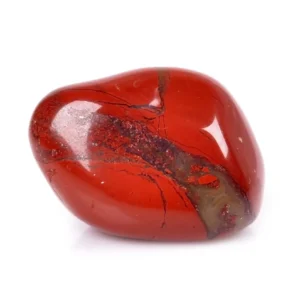 Macro studio close-up of a single mirror-polished natural Red Jasper tumbled stone isolated on a seamless white background, highlighting rich crimson-red chalcedony crossed by a natural brecciated quartz and hematite mineral vein.